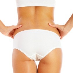 close up of female buttocks in white undergarments with hands on hips in front of white background