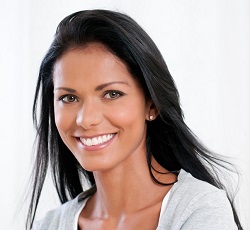 close up of woman smiling with hair blowing in front of white background